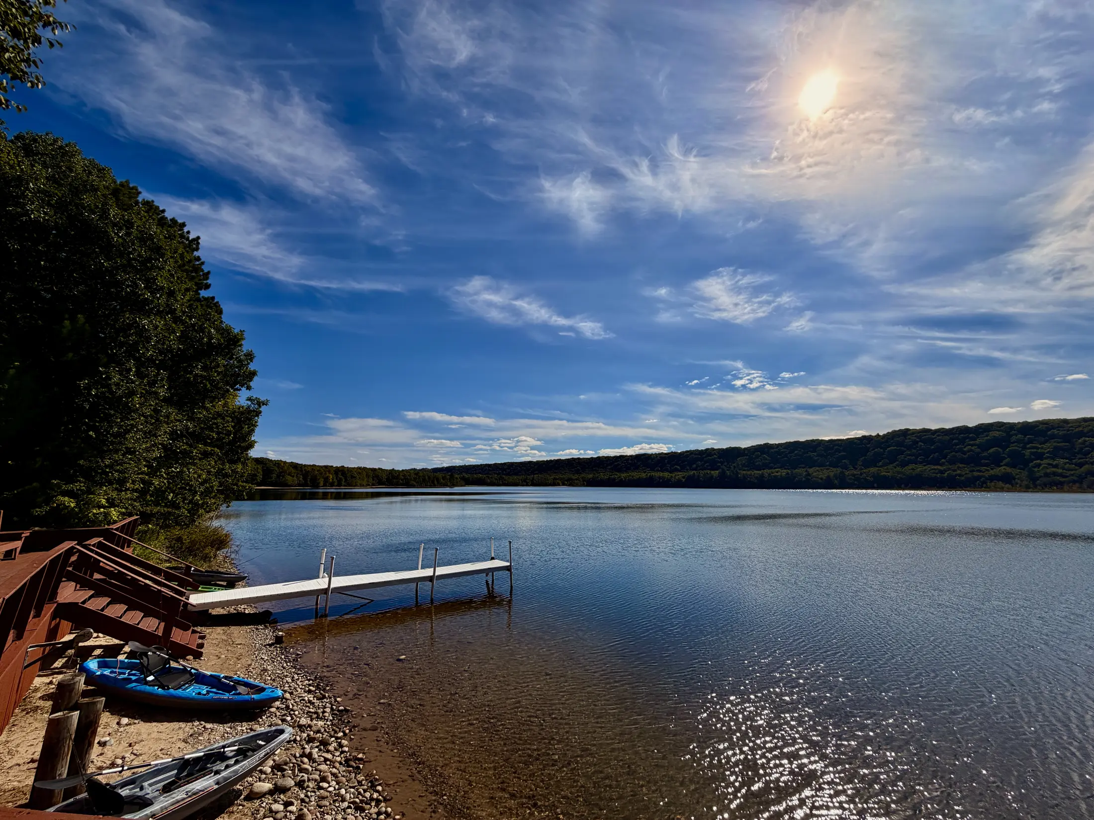 Sun over Monocle Lake with the private dock, shoreline and edge of the deck